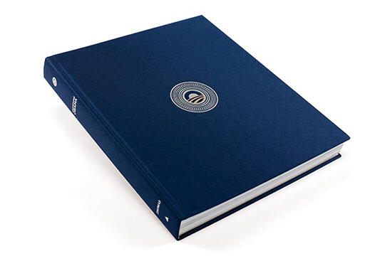 A dark blue hardcover book featuring a circular emblem in the center of the cover, set against a plain white background.