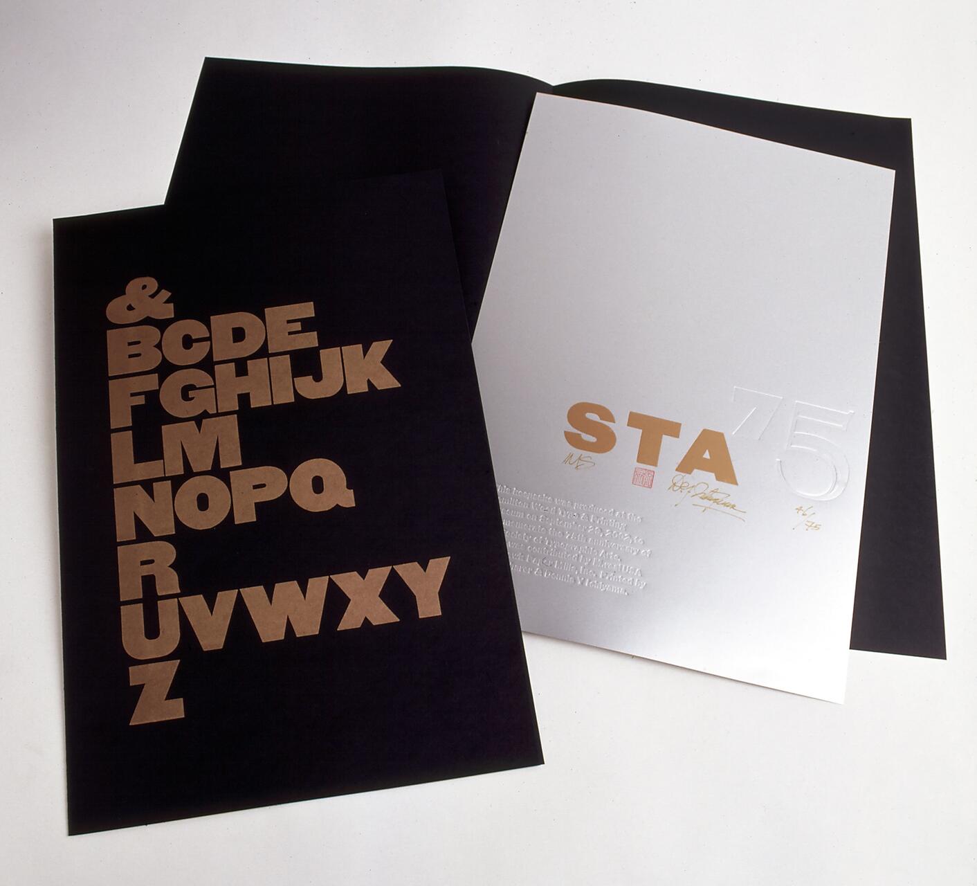 Black and white pages with bold, gold uppercase letters on one side and embossed text on the other side, lying on a white background.