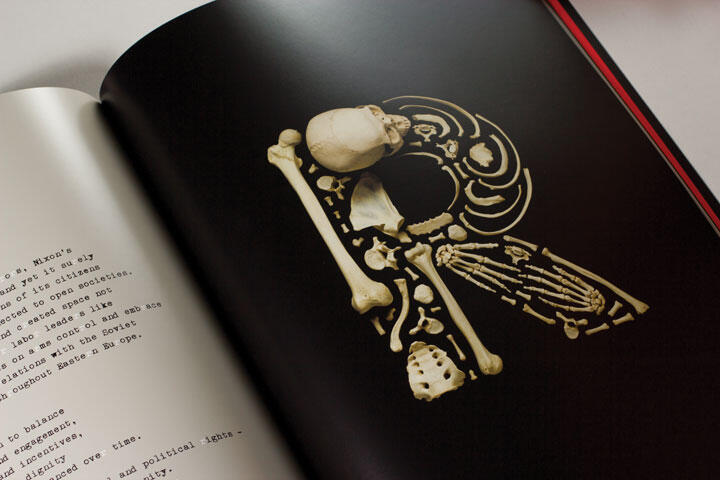 Skeleton of a bird arranged on a black page, surrounded by text on the left page of an open book.