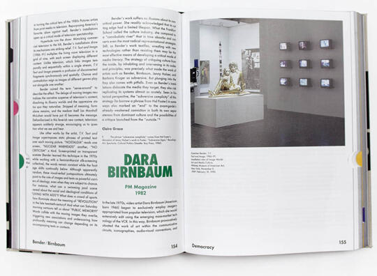 Open book displaying two pages; left page has text and right page features text and a photograph of an art installation with a golden figure and several small screens on a wall.