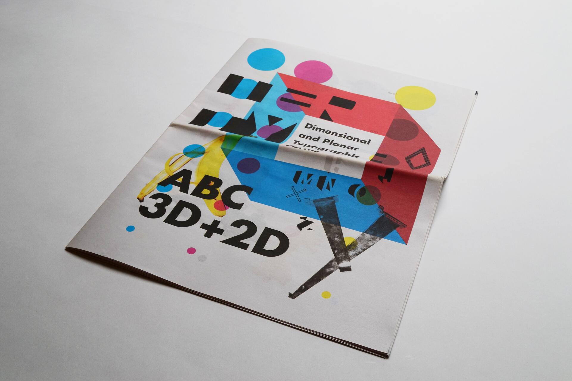 Colorful folded magazine on a white surface, featuring bold, abstract typography and graphics with bright circles and squares in red, blue, and yellow. The text is layered with artistic elements.