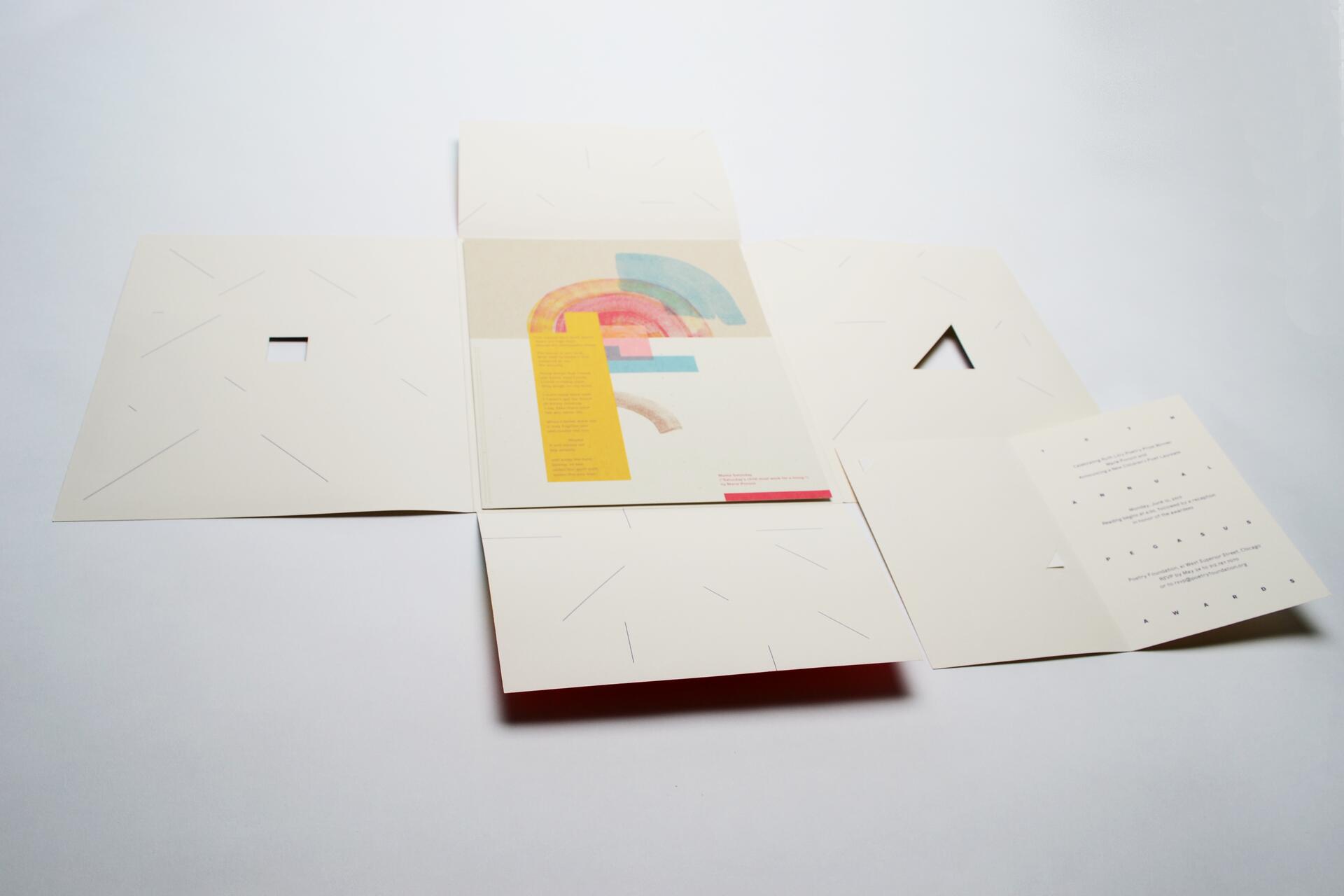 Folded paper with cut-out designs partially open, revealing colorful geometric shapes and text inside.