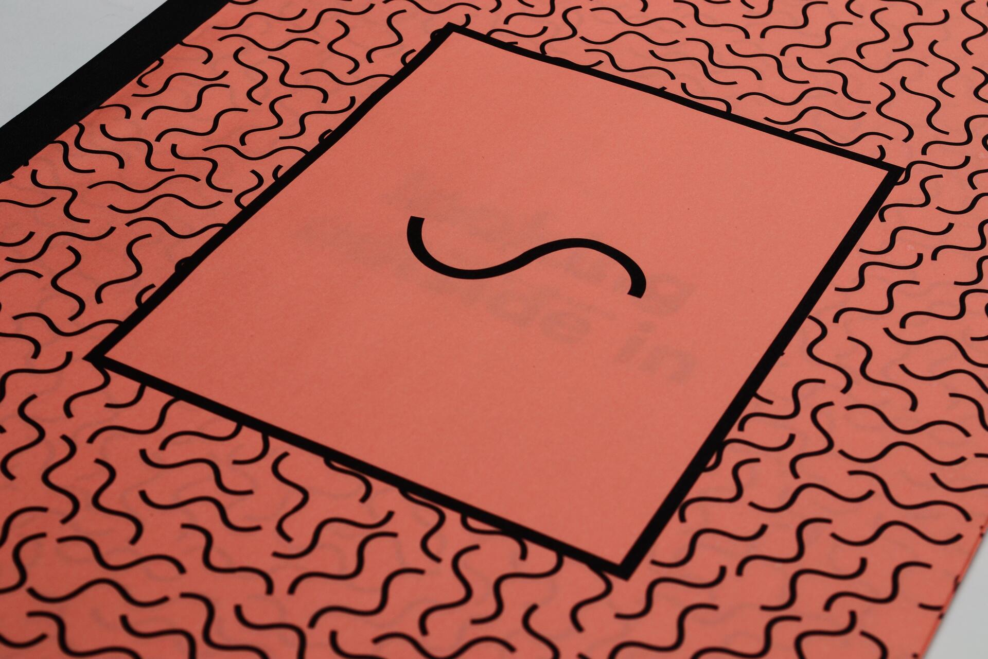 Red paper with a black squiggly pattern and a central square featuring a large black letter "S".