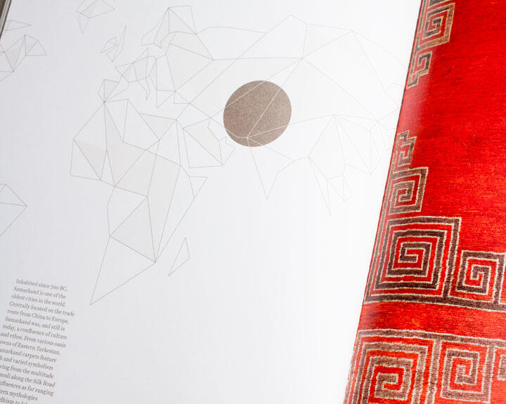 Geometric world map illustration with a brown circle on a white page, next to a richly textured red carpet design featuring intricate square spiral patterns.