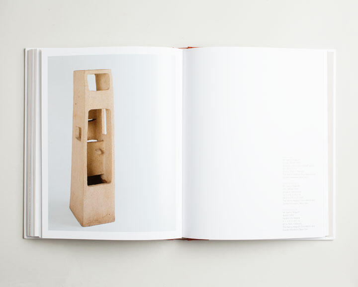 Open book showing a page with a photo of a tall, rectangular beige sculpture with various cutouts.