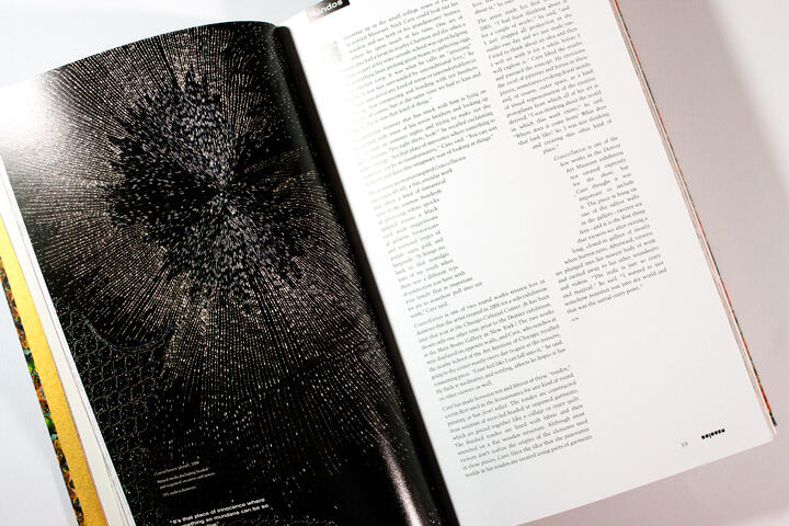 Open magazine showing a page with a complex black and white graphic resembling an abstract burst on the left, and a page of dense text with a large circular blank space in the middle on the right.