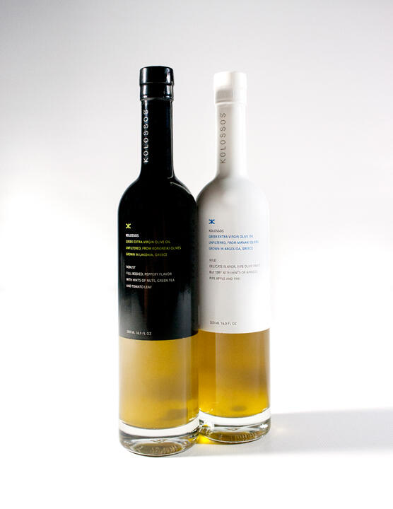 Two bottles of olive oil, one with a black label and another with a white label, standing on a white surface.