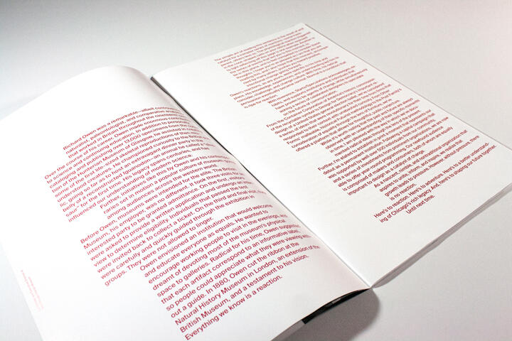 Open magazine with pages of red text on a white background, photographed at an angle.