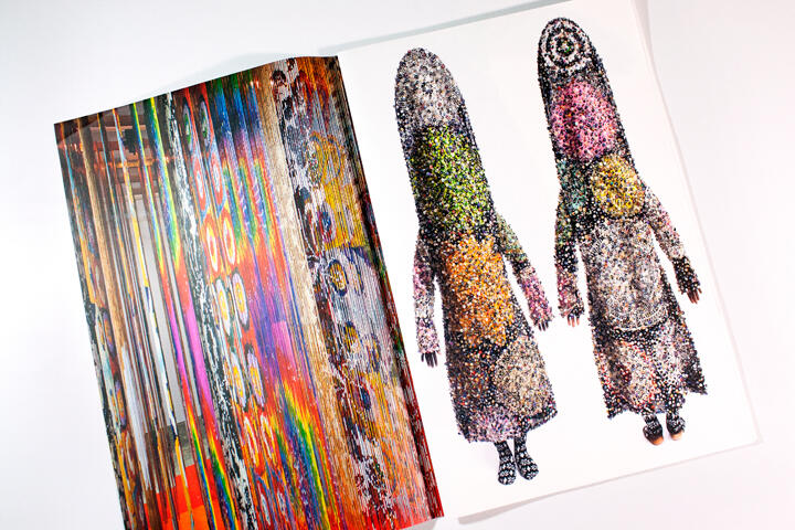 Open magazine with colorful abstract artwork on the left page and two tall, textured, multicolored figures on the right.