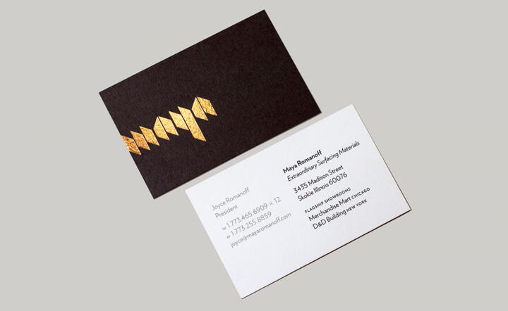 Two business cards: one black with a gold geometric pattern, and one white with contact information.