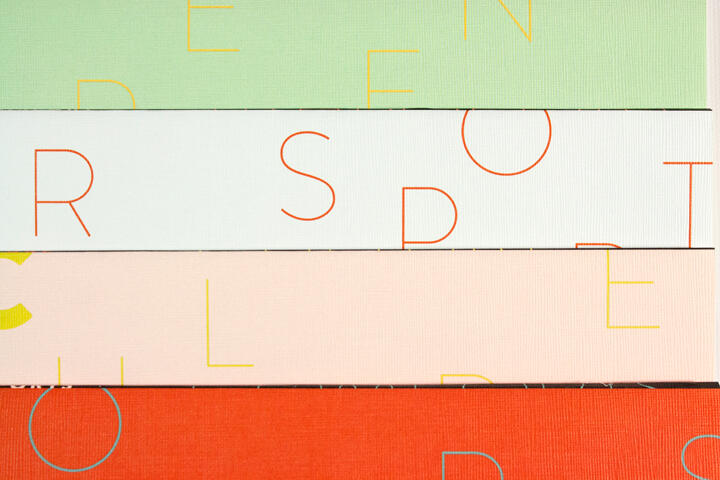 Stacked colorful panels with partial letters, featuring green, light blue, peach, and red-orange backgrounds, creating a modern abstract design.