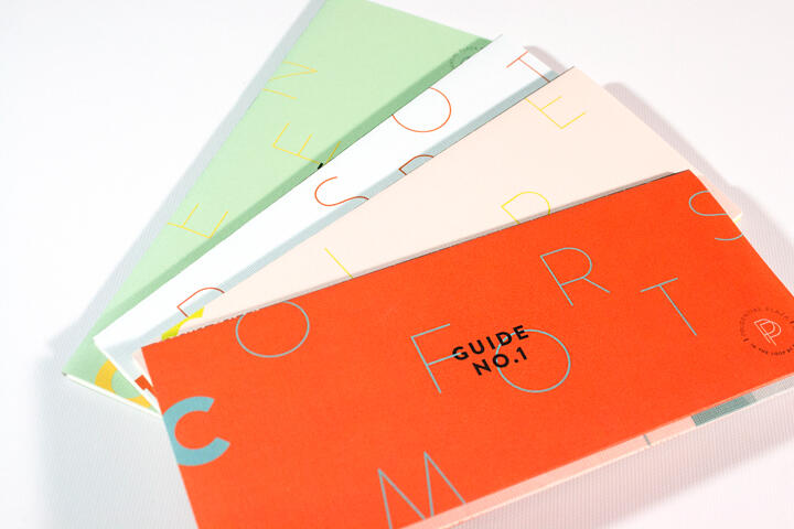 Colorful brochures with overlapping covers in pastel green, white, and orange, featuring minimalist typography. Front cover reads "Guide No. 1" in a modern design.