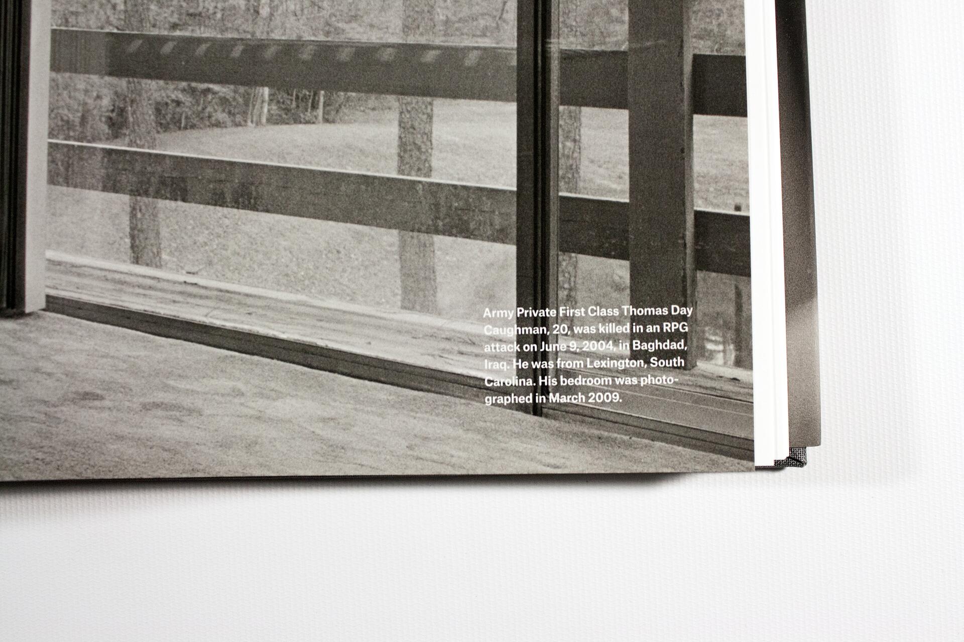 Black and white photograph of a room with a large window showing an outdoor scene of trees and grass. Printed text overlay details personal information and dates related to Army Private First Class Thomas Day Caughman.