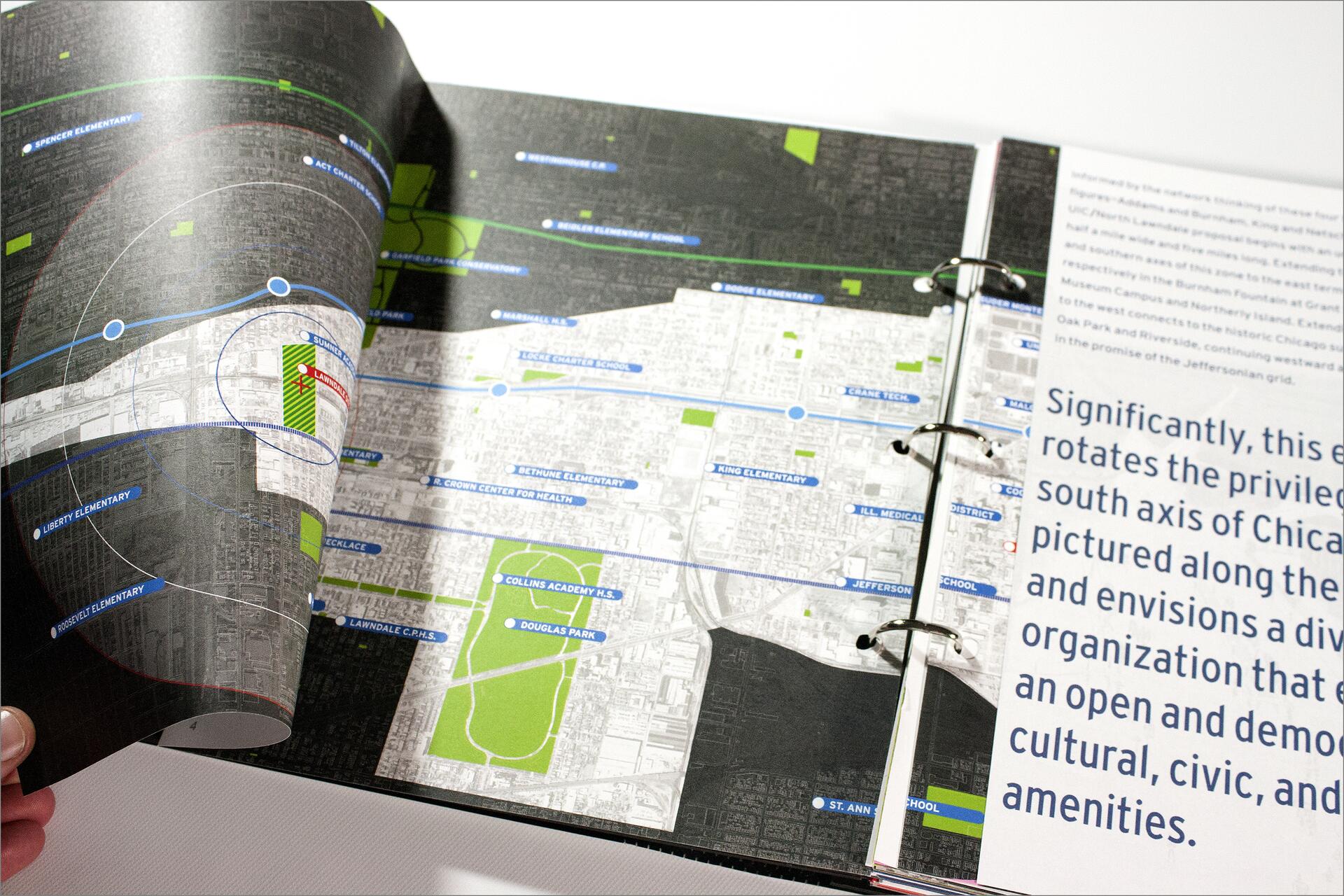 An open binder contains a detailed map of a city, showcasing schools and health centers marked in blue and green. A partially visible adjacent page includes text with large, bold letters.