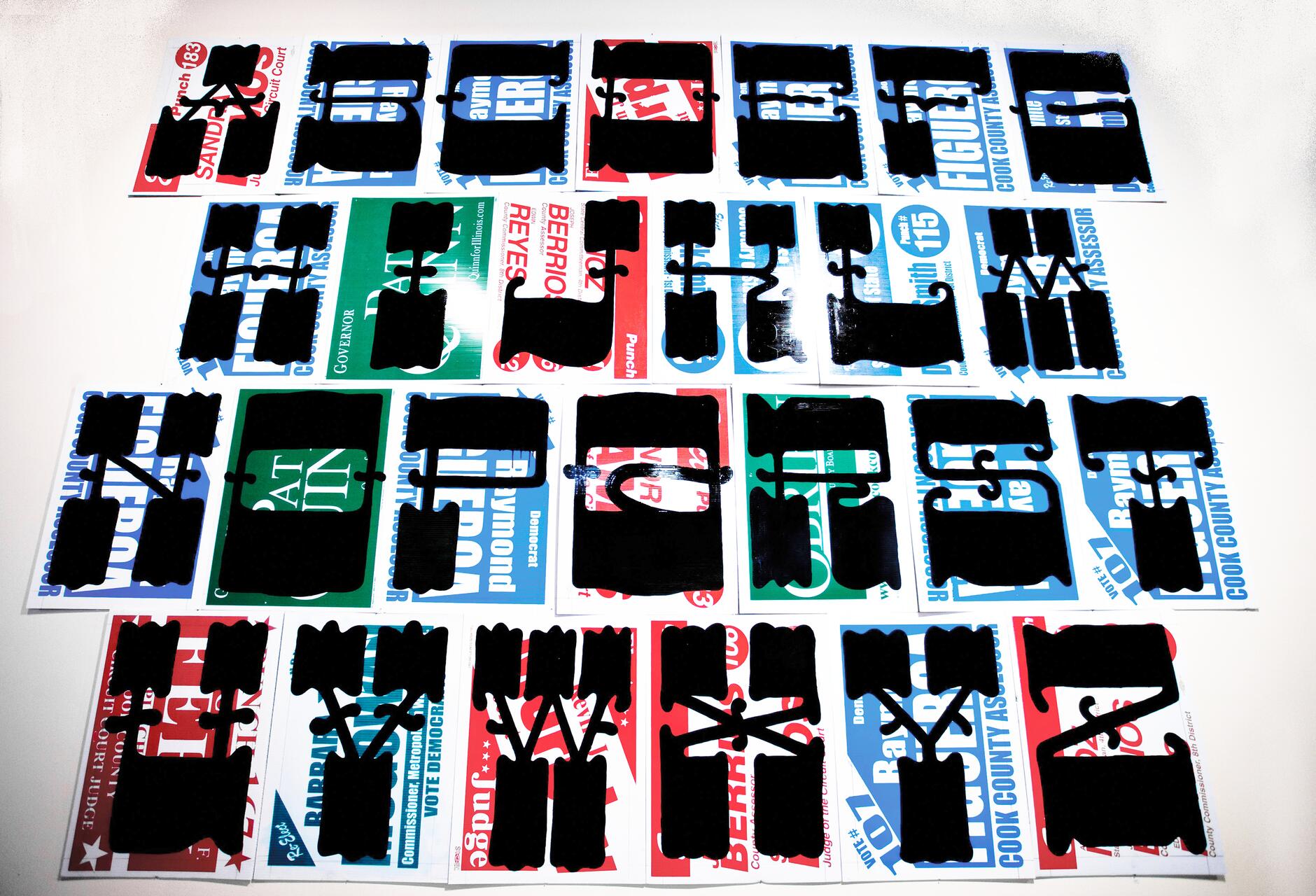 Overlapping black stencil letters on brightly colored political campaign flyers arranged on a surface.