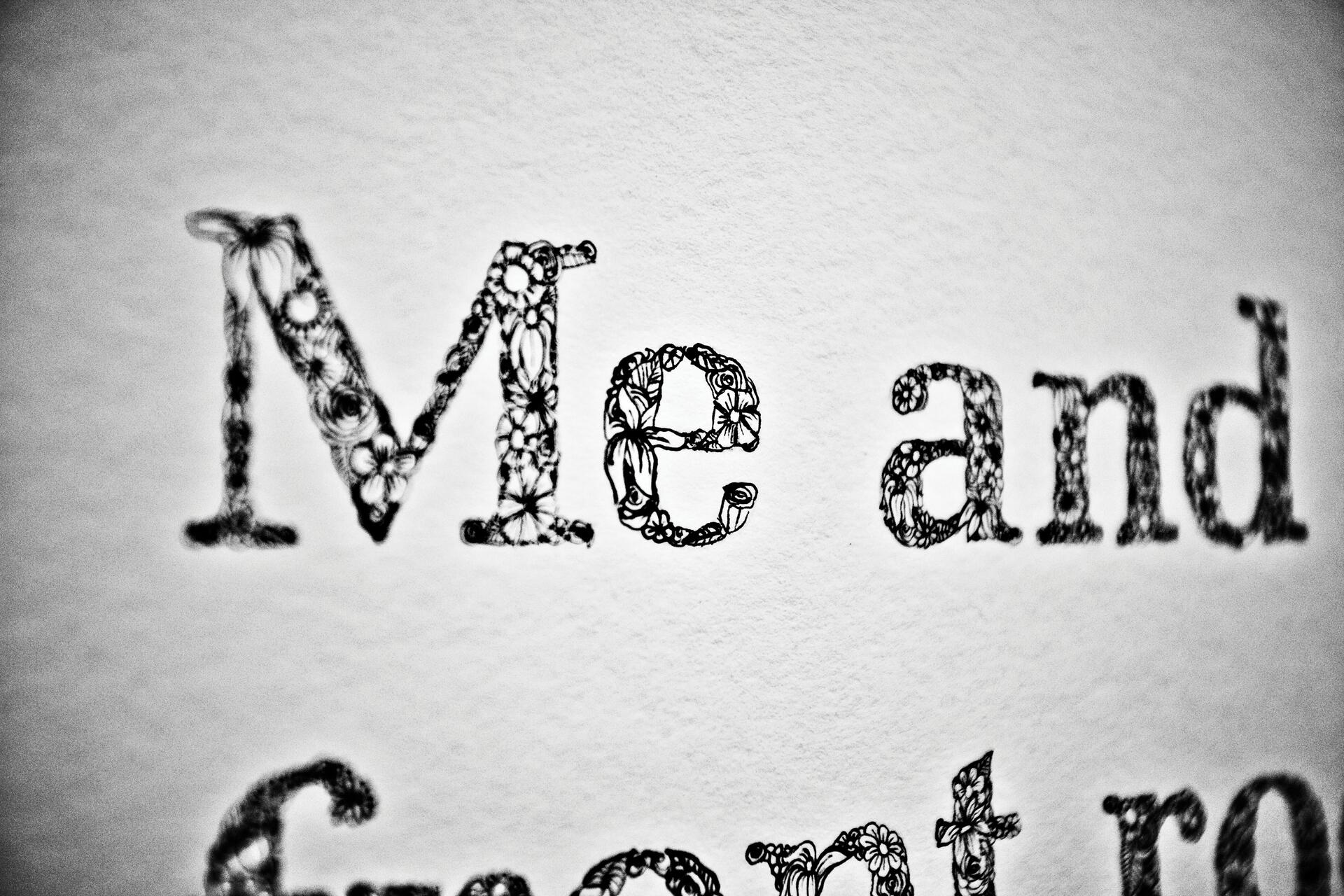 The word "Me" is intricately crafted with floral patterns in black ink on white paper.