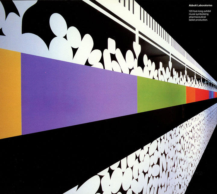 Abstract mural with white geometric shapes on a black background, featuring horizontal bands of orange, purple, green, and red colors. Appears to represent tablet production.