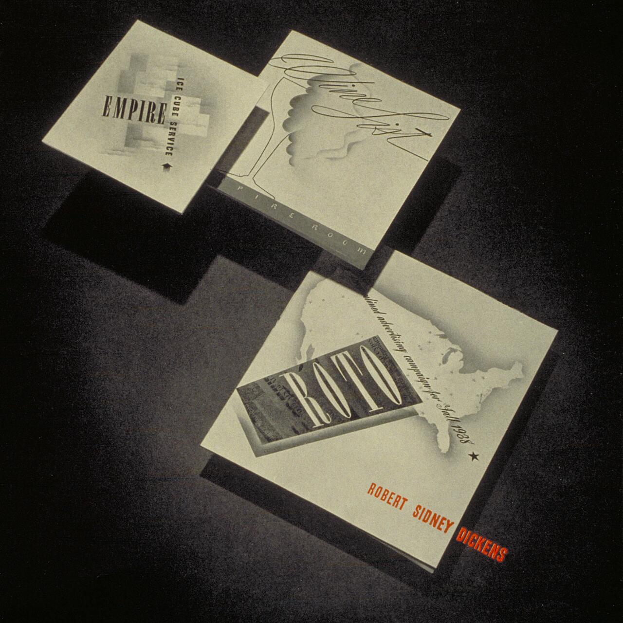 Three black and white graphic designs arranged on a dark surface. The designs feature text elements and abstract shapes. A map and stylized text are visible. Shadows cast by the designs add depth to the composition.