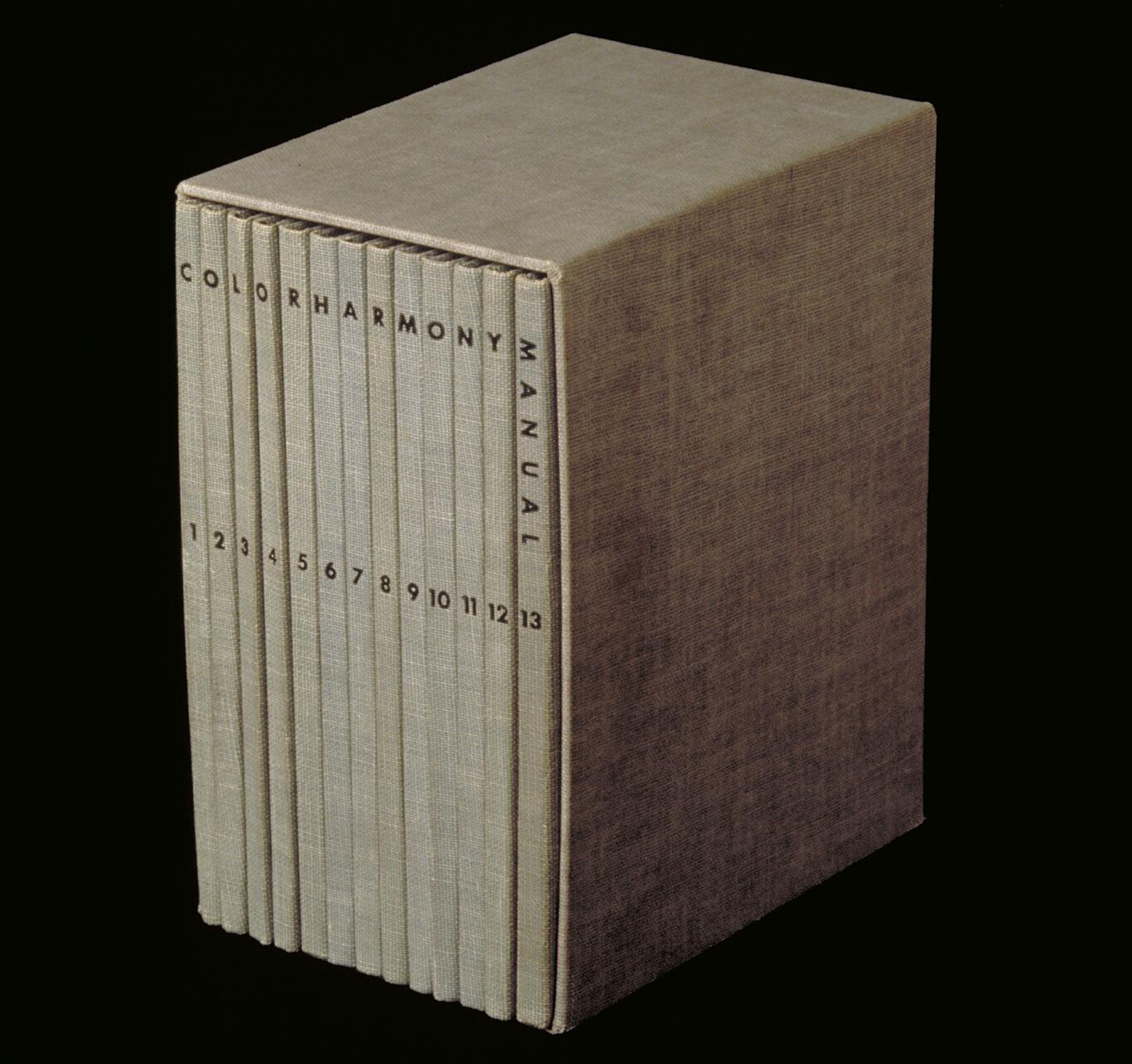 Box containing 13 volumes of the "Color Harmony Manual" with beige covers and numbered spines, set against a black background.