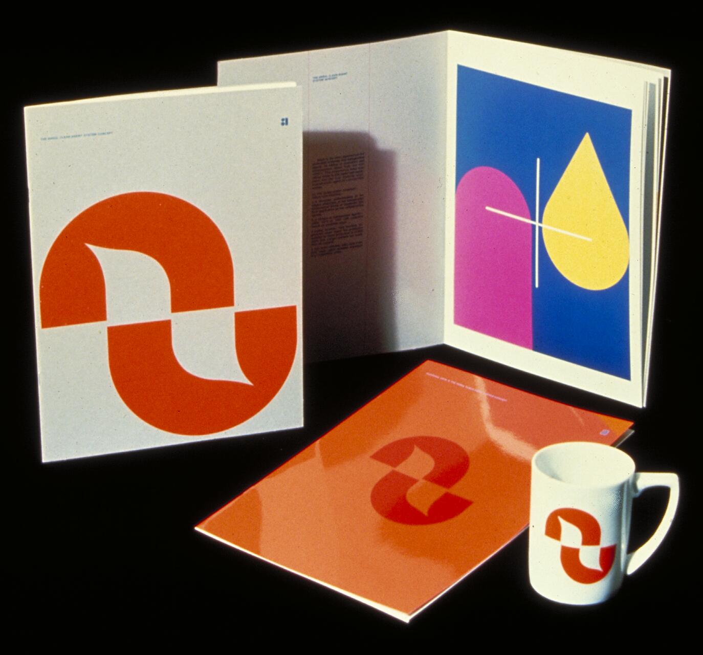 Stationery set with a modern logo featuring red and orange abstract shapes on white surfaces, including a folder, open booklet with geometric art, notebook, and mug.