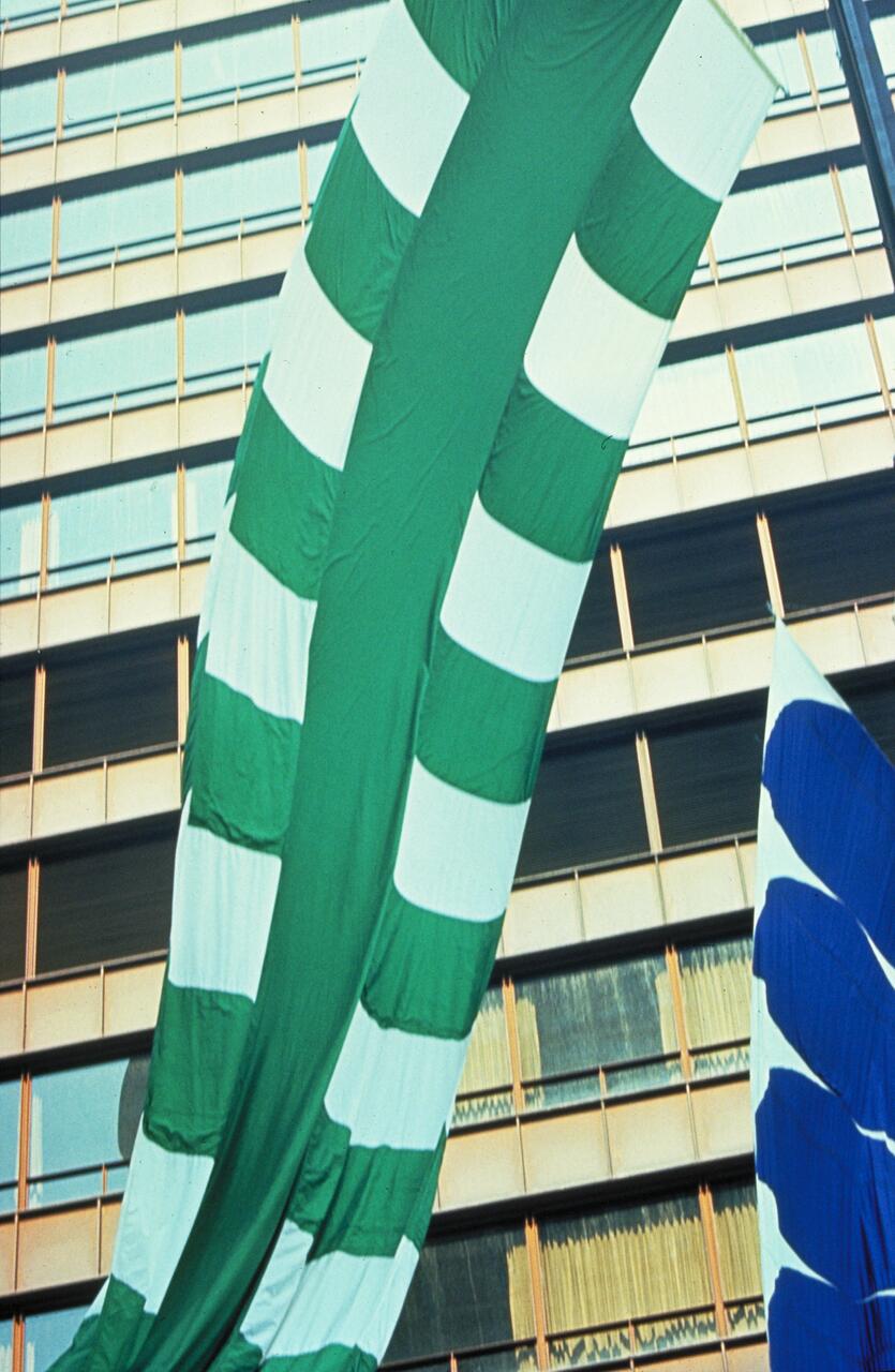 Large green and white striped flag drapes down a building facade with reflective windows, a blue and white striped section visible on the right.