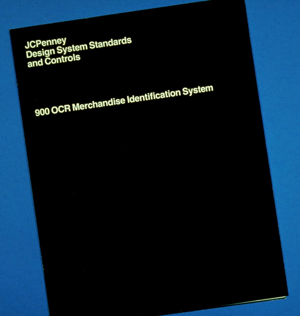 Black cover of a JC Penney manual titled "Design System Standards and Controls, 900 OCR Merchandise Identification System" on a blue background.