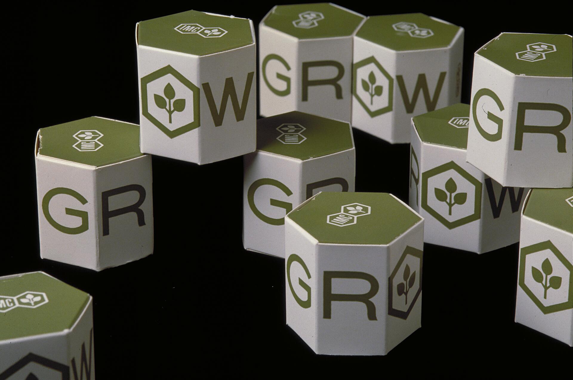 Hexagonal blocks with green tops arranged to spell "GROW," each featuring a leaf icon and logo.