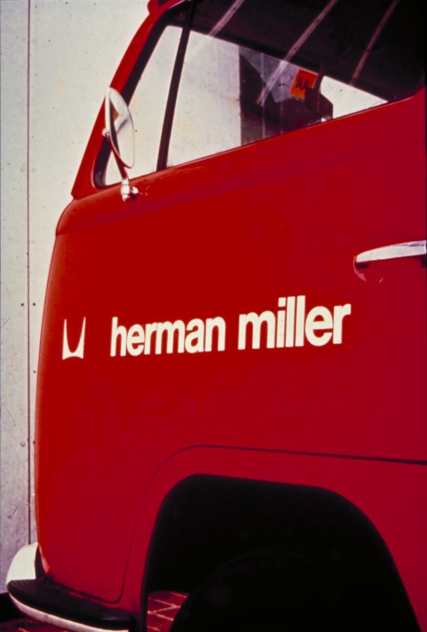 Red van with "herman miller" and logo on the side, featuring a white curved roof and mirror.