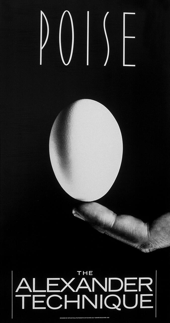 A white egg balanced on the tip of a person's fingers against a black background.