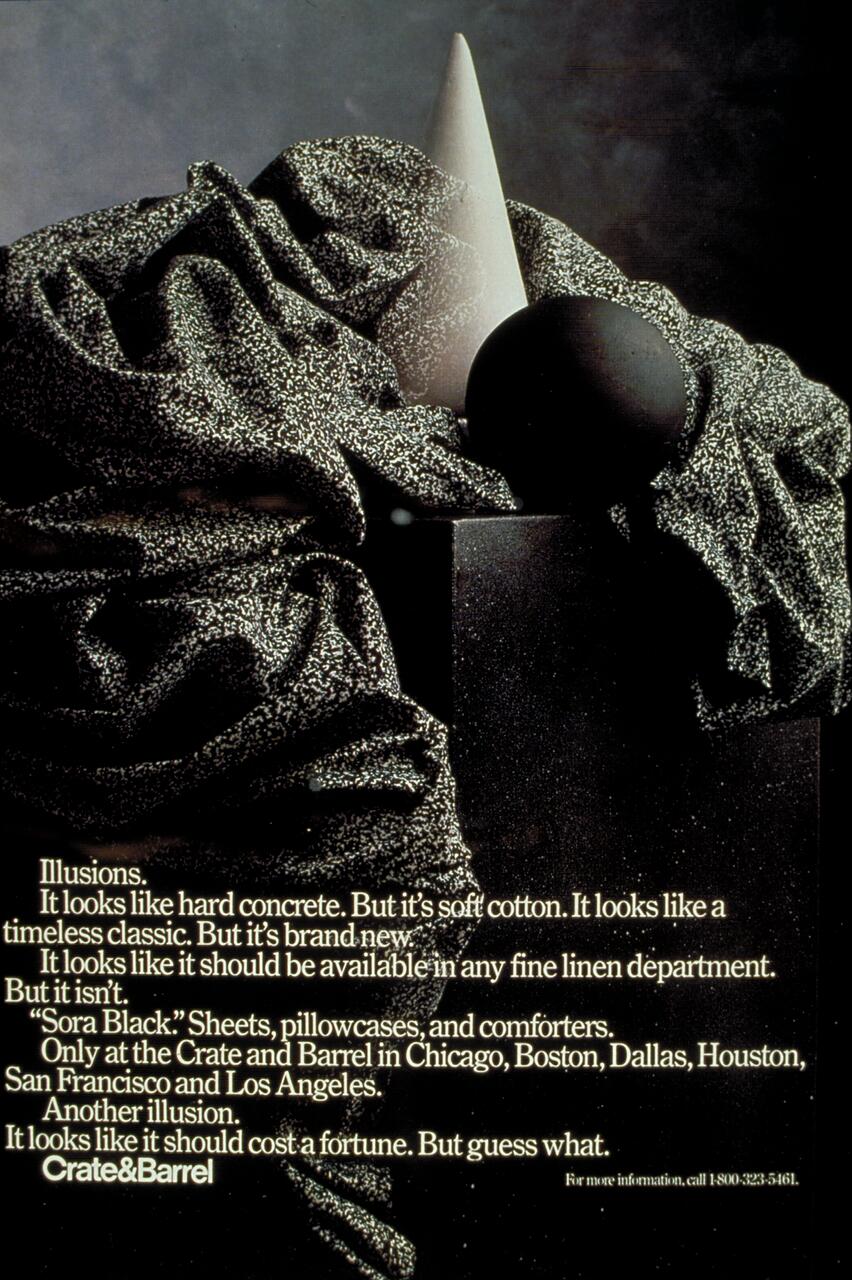 Artistic composition with textured black fabric draped over geometric shapes including a cone and sphere, creating a visually intriguing contrast between smooth and rough surfaces. The setting is dramatic, with shadows enhancing the textures and forms.