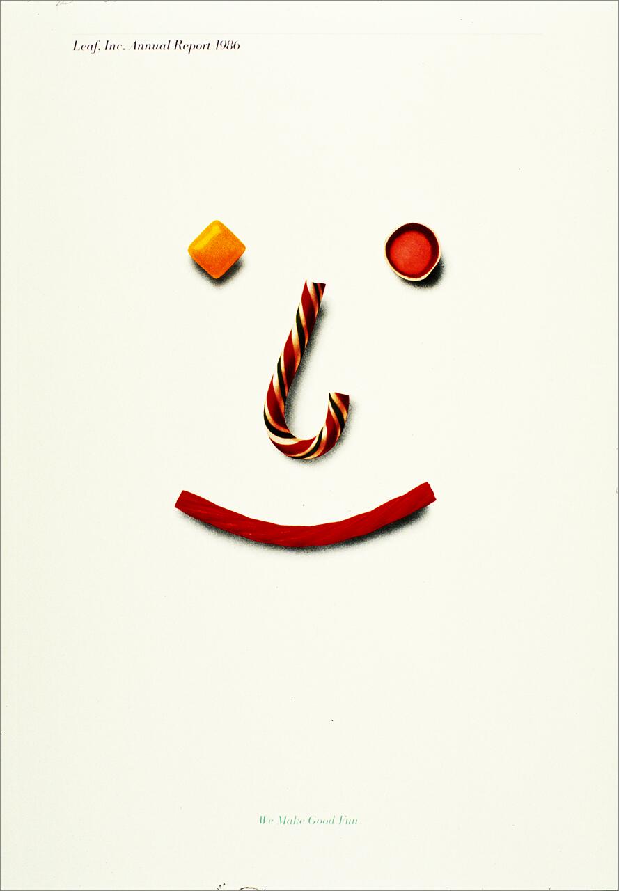 Face made with candy: a twisted striped candy cane for a nose, a red candy for the mouth, a yellow square candy for one eye, and a round candy for the other, on a plain background.
