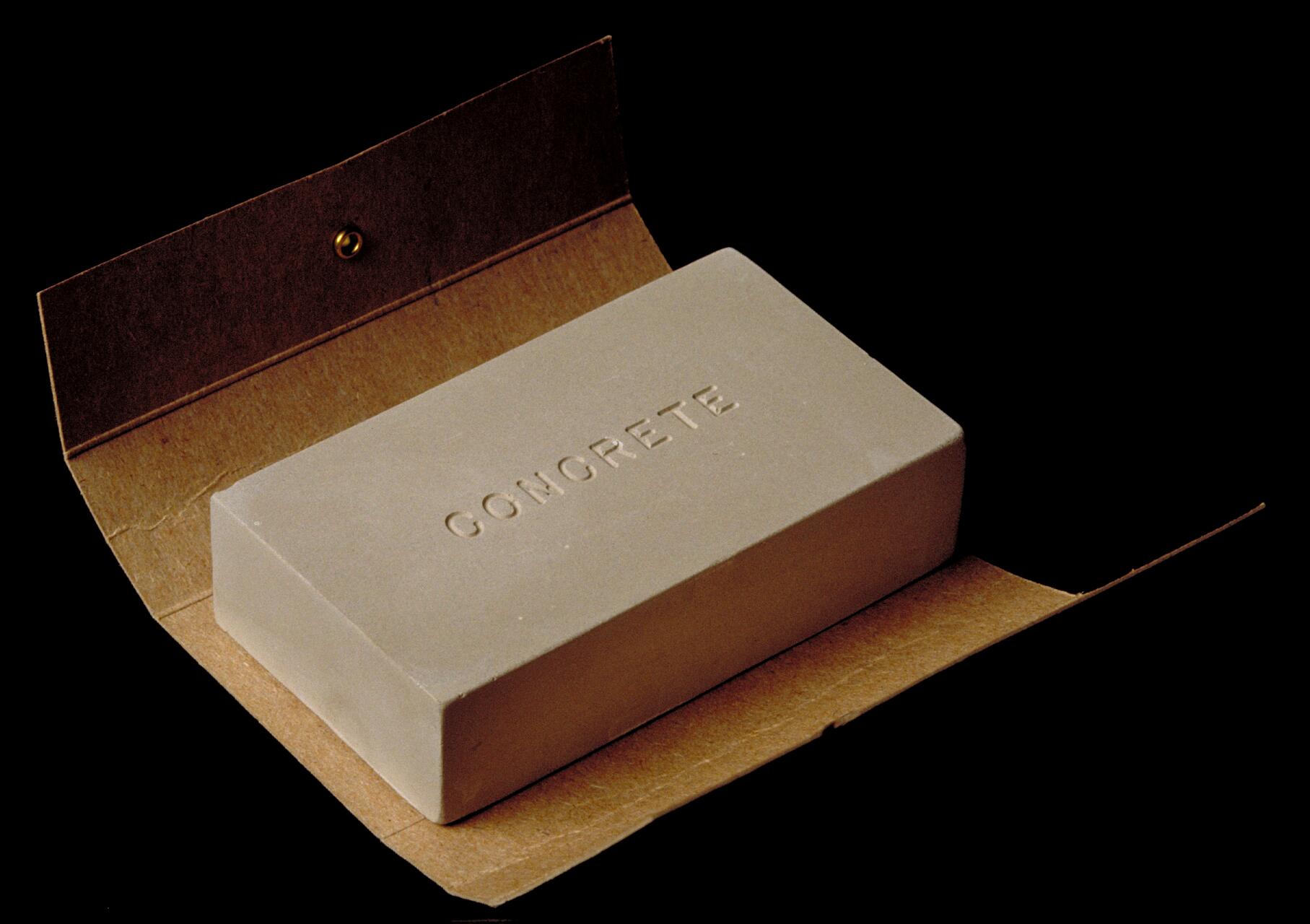 Bar of "Concrete" soap in brown cardboard packaging on a black background.