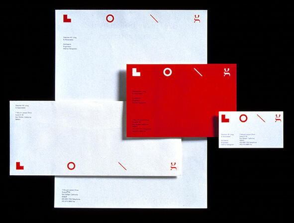 Stationery set with white paper featuring minimalist red geometric shapes and text. Includes a red envelope and smaller business card, arranged against a dark background.