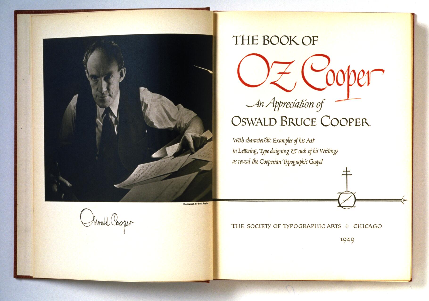 Open book featuring a black-and-white photograph of a man working at a desk with papers, captioned with his name. The right page displays the title "The Book of Oz Cooper" with decorative typography and publication details from the Society of Typographic Arts, Chicago, 1949.