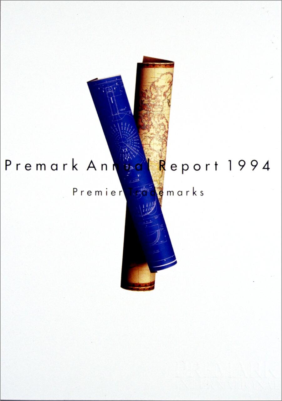 Two rolled papers, one blue with technical drawings and one beige with a map, placed against a plain white background. Text overlaying the image reads "Premark Annual Report 1994."