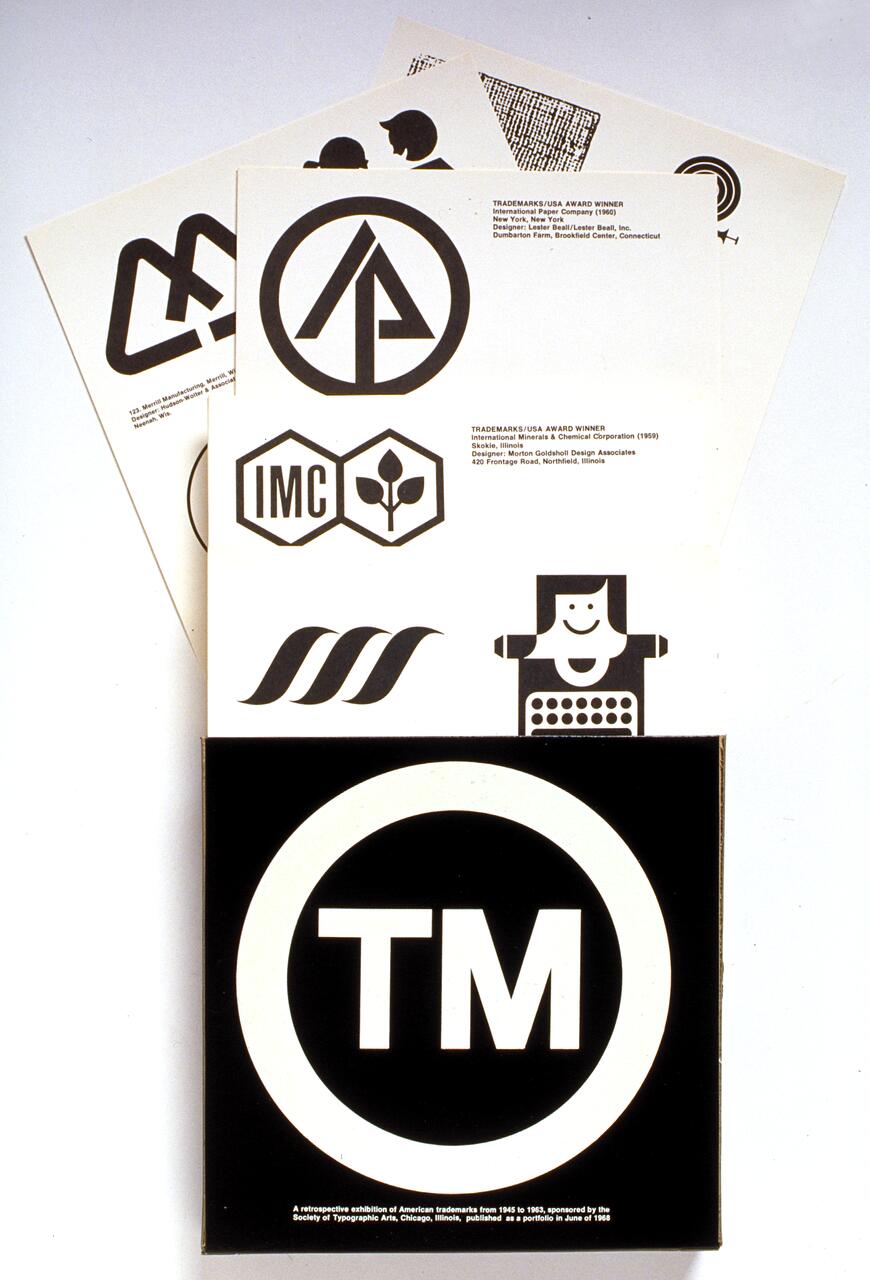 Several sheets of paper displaying various black-and-white logos, including geometric and abstract designs. A large trademark symbol in a black circle is prominent in the foreground.